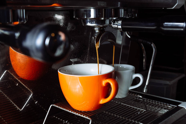 Φρεσκοπαρασκευασμένος καφές χύνεται από τη μηχανή καφέ σε κύπελλα. Χύτευση, ποτά. - Φωτογραφία, εικόνα