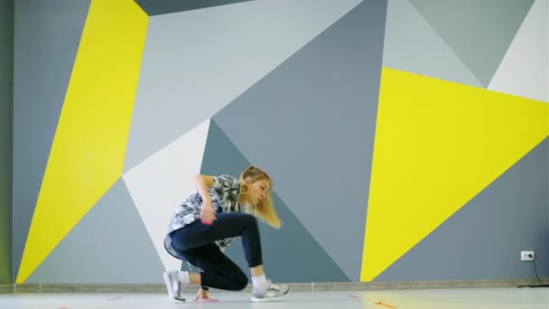 Veselý mladý dívka tanec hip hop ve studiu před stěnou s jasným geometrickým vzorem. - Záběry, video