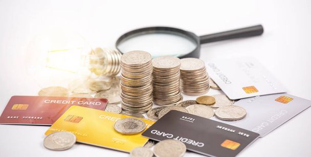 Münzen mit Kreditkarte und Glühbirne auf weißem Hintergrund für Finanzen und Bankwesen, Sparen von Ideen und Investitionsbudget, Kreative Ideen zum Sparen - Foto, Bild