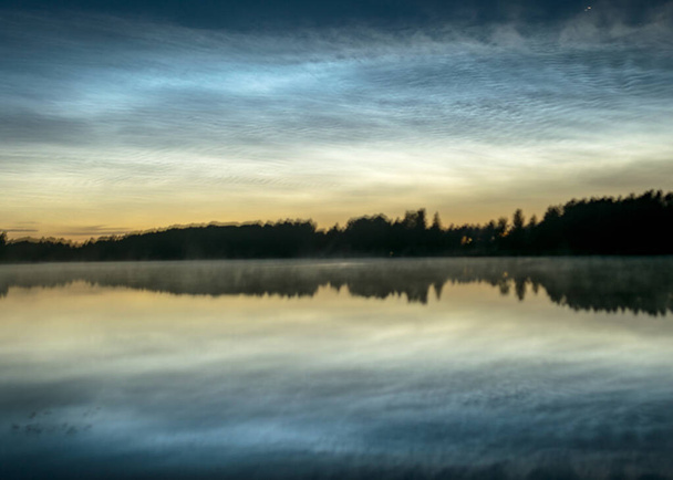 湖の上に白い銀の雲と美しい夜の風景,ぼやけた前景,湖の水の中に魅力的な雲の反射,夏の夜 - 写真・画像