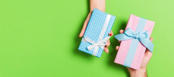 Top view of a woman and a man exchanging gifts on colorful background. Couple give presents to each other. Close up of making surprise for holiday concept. - Photo, Image