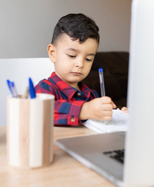 jongen tekening in een notitieboekje op het bureau tafel thuis - Foto, afbeelding