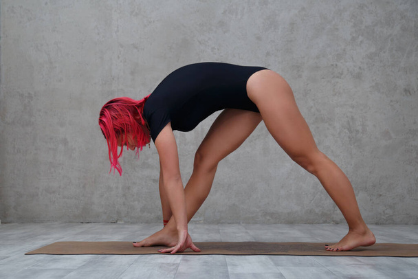 A girl with pink hair practices yoga. - Zdjęcie, obraz