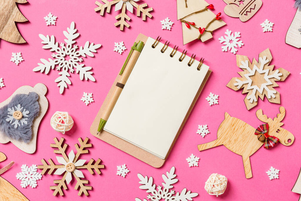 Vista superior del cuaderno sobre fondo rosa hecho de decoraciones navideñas y juguetes. Concepto de adorno de Navidad. - Foto, Imagen