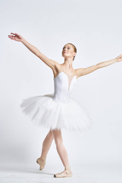 Beyaz etekli bir balerin hafif bir arka planda dans etti. - Fotoğraf, Görsel