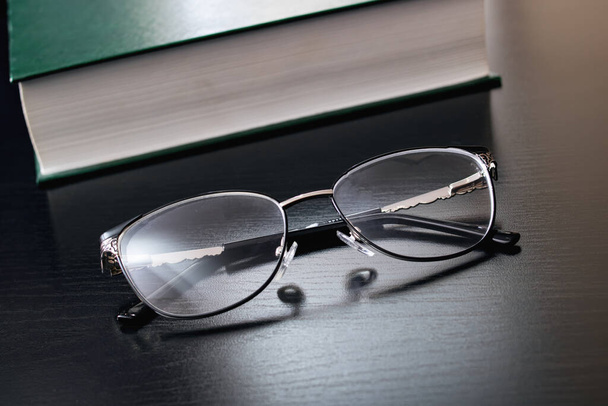 Glasses and green book on a wooden table - Фото, зображення