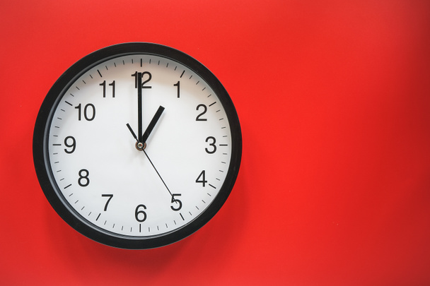 Аналоговые классические черно-белые часы на красном фоне  - Фото, изображение