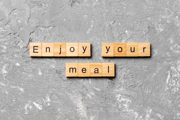Aproveite sua palavra refeição escrito no bloco de madeira. Aproveite o seu texto refeição na mesa de cimento para a sua desing, conceito. - Foto, Imagem