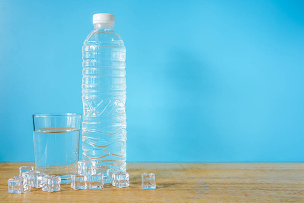 Mesa de textura de madera y vaso de agua con botella de plástico  - Foto, Imagen