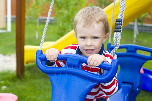 Portret van de vier-jaar-oude jongen op een schommel - Foto, afbeelding