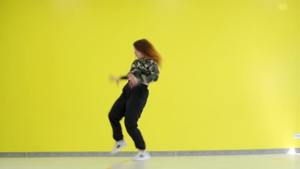 Vrolijk jong meisje dansen moderne jeugd choreografie gratis stijl tegen gele muur achtergrond. geïsoleerd. - Video