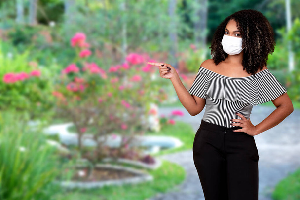 Außenporträt einer jungen schwarzen Frau mit medizinischer Schutzmaske. Ausbruch des Corona-Grippe-Virus, Covid 19 mit Kopierplatz. - Foto, Bild