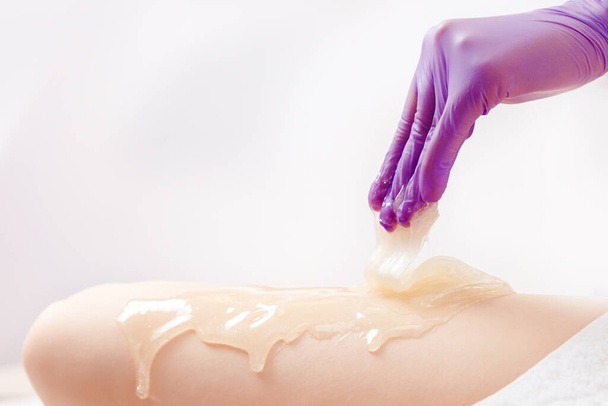 Enlever les poils de la peau des pieds avec de la pâte de sucre liquide, renouveler l'épithélium et nettoyer les pores de l'acné - Photo, image