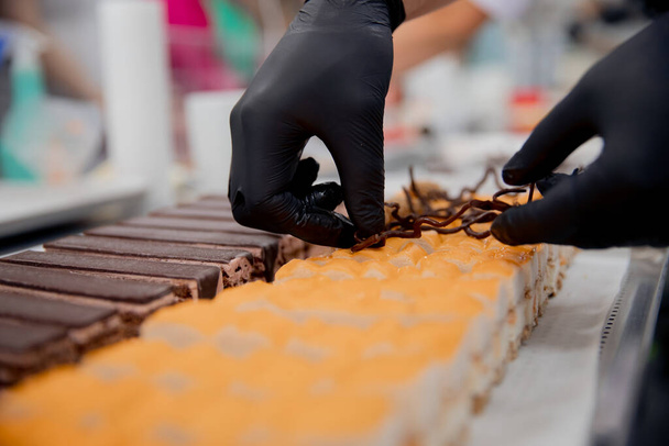 Detailní záběr šéfkuchařských rukou připravujících koláče a dezerty pokryté čokoládovou polevou - Fotografie, Obrázek