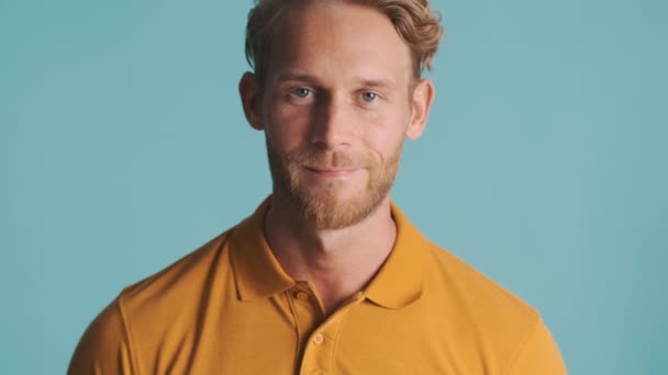Atractivo hombre barbudo rubio posando con confianza en la cámara sobre fondo colorido - Imágenes, Vídeo