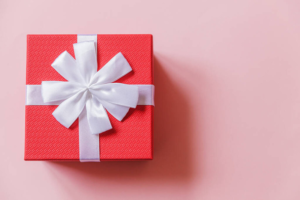 Karácsony újév születésnapja Valentin-napi ünneplés jelen romantikus koncepció. Egyszerűen minimális design piros ajándék doboz elszigetelt pasztell rózsaszín színes háttér. Lapos feküdt felső nézet másolási hely - Fotó, kép