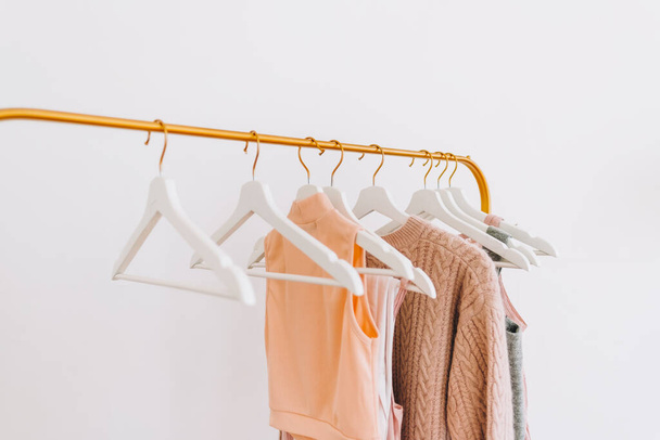 Perchero de armario dorado con ropa de moda de color pastel cerca de la pared blanca. Concepto de compras. Foto de alta calidad - Foto, Imagen