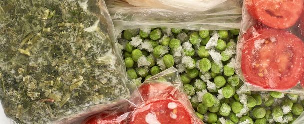 Set von Tiefkühlkost in Säcken verpackt. Gemüse für den Winter aufbewahren, von oben gesehen. Tomaten, grüne Erbsen, Grünzeug. - Foto, Bild