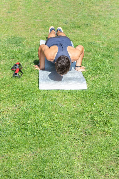 молодий чоловік біжить тренування з штовханням на килимок в сонячний день в саду
 - Фото, зображення