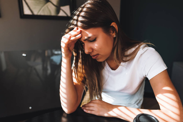 Young frustrated woman working at office desk in front of laptop, suffering from chronic daily headaches, online treatment, medical consultation appointment. High quality photo - Fotografie, Obrázek