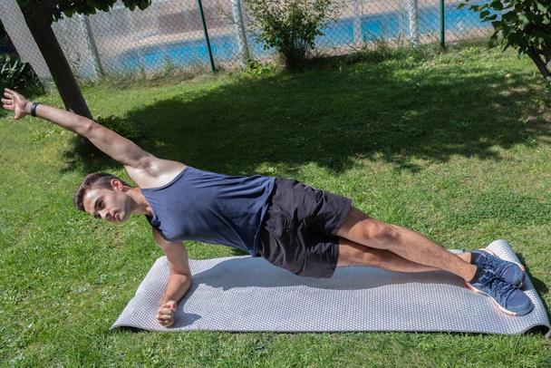teenager doing push-up exercises to strengthen muscles in the garden - Photo, Image