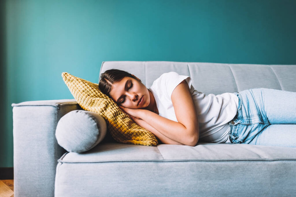 Young caucasian woman lying on sofa in living room sleeping after hard-working day, tired millennial female fall asleep on couch at home, take nap or daydream, fatigue concept. High quality photo - Foto, imagen