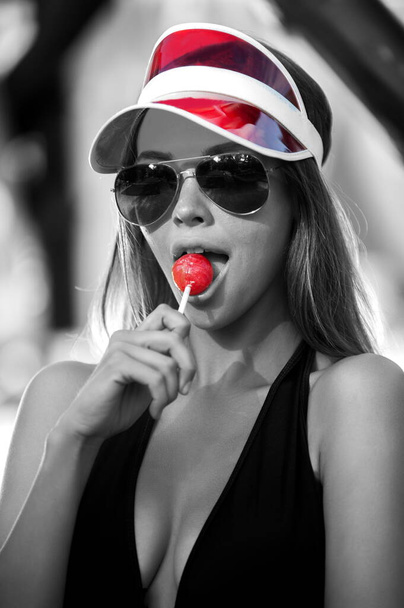 Portrait of beautiful woman in sun visor with lollipop - Фото, изображение