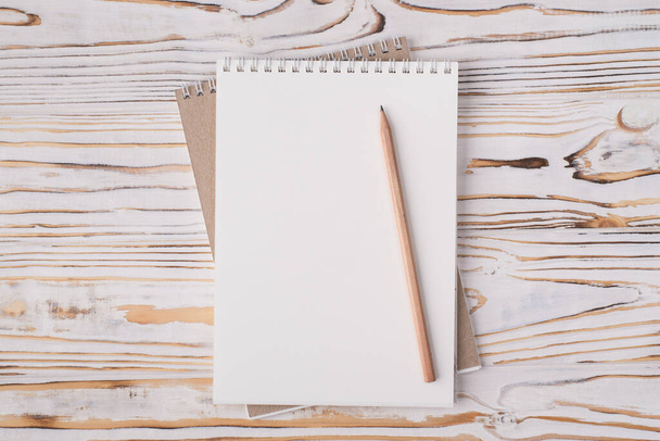 Topo acima vista aérea plana leigos foto de um caderno em branco e lápis de madeira isolado no fundo de madeira leve com copyspace - Foto, Imagem