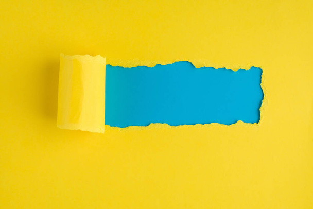 Bovenkant bovenaanzicht foto van gescheurd geel papier over blauwe achtergrond met kopieerruimte - Foto, afbeelding