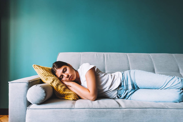 Young caucasian woman lying on sofa in living room sleeping after hard-working day, tired millennial female fall asleep on couch at home, take nap or daydream, fatigue concept. High quality photo - Foto, afbeelding