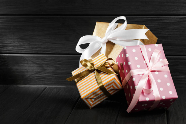 Κουτί δώρου με κορδέλα σε μαύρο ξύλινο φόντο - Φωτογραφία, εικόνα