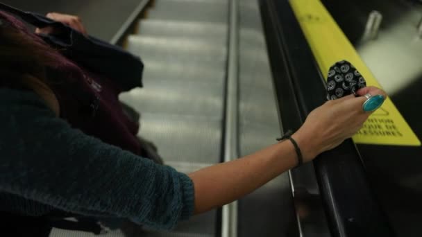 Máscara de mano mujer de pie en escaleras mecánicas - Metraje, vídeo