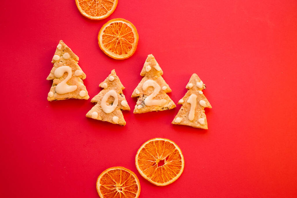 Gingerbread cookies. 2021 numbers. New year greeting card. Top view. Vivid Red background. Dried oranges. Zero waste Christmas gift  - Photo, Image