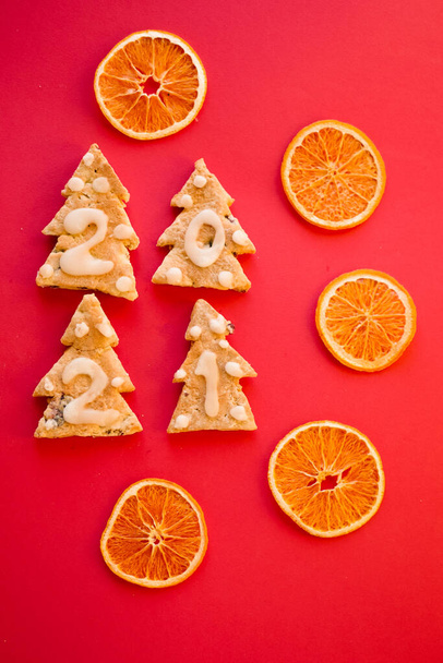 Gingerbread cookies. 2021 numbers. New year greeting card. Top view. Vivid Red background. Dried oranges. Zero waste Christmas gift. Vertical orientation  - Photo, Image