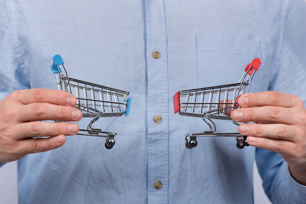 Male hands holding two toy grocery cart. Shopping concept. - Photo, image