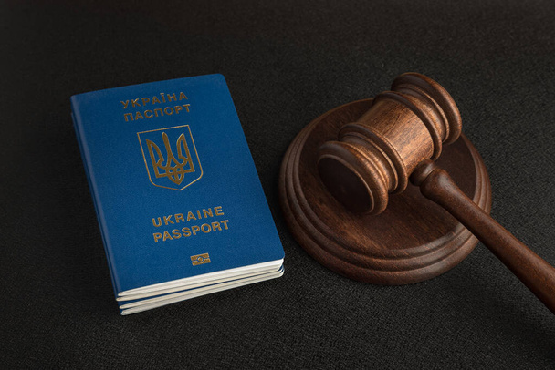 Διαβατήριο πολίτη της Ουκρανίας και ένα δικαστικό σφυρί σε μαύρο φόντο. Νόμιμη μετανάστευση. Απόκτηση ιθαγένειας - Φωτογραφία, εικόνα