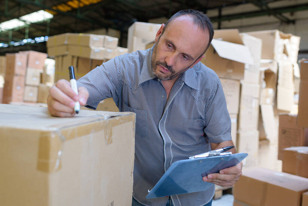 a warehouse worker writing on boxes - Fotografie, Obrázek