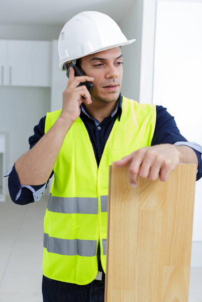builder on phone holding plank - Fotografie, Obrázek