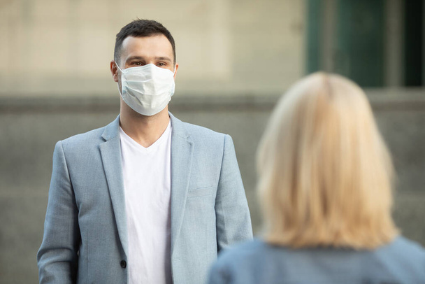 Man and woman wearing protective face masks standing 2 m from each other keeping social distancing avoiding the spread of coronavirus. Covid-19.  - Foto, imagen