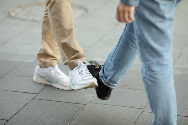 Young people greeting to avoid the spread of coronavirus. Two friends meet, instead of greeting with a hug or handshake, they touch their feet together. Social distance concept. Covid-19. - Foto, imagen