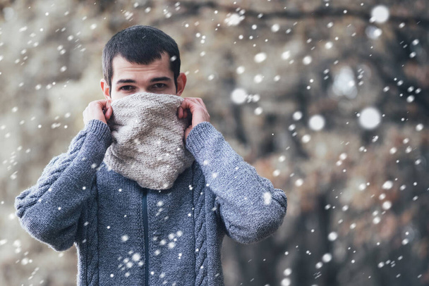 Mężczyzna w swetrze z dzianiny. przykrywa twarz ciepłym szalikiem z zimna - Zdjęcie, obraz