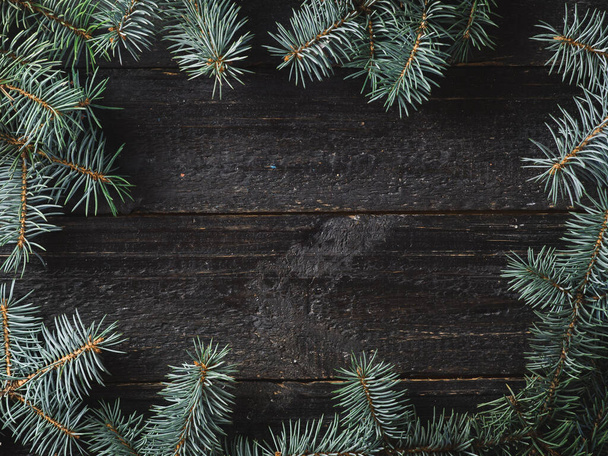 Χειμώνας και Χριστούγεννα φόντο. Χριστουγεννιάτικο δέντρο κλαδιά σε σκούρο ξύλινο φόντο με copyspace στο κέντρο - Φωτογραφία, εικόνα