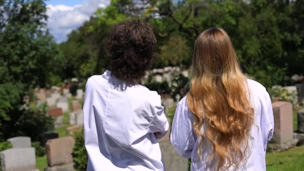Twee vrouwen op het kerkhof praten wat rond. - Video