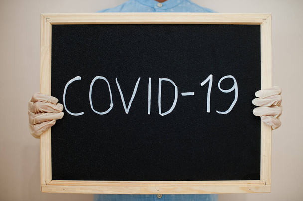 Covid-19. Coronavirus concept. Boy in gloves hold inscription on the board. - Photo, Image