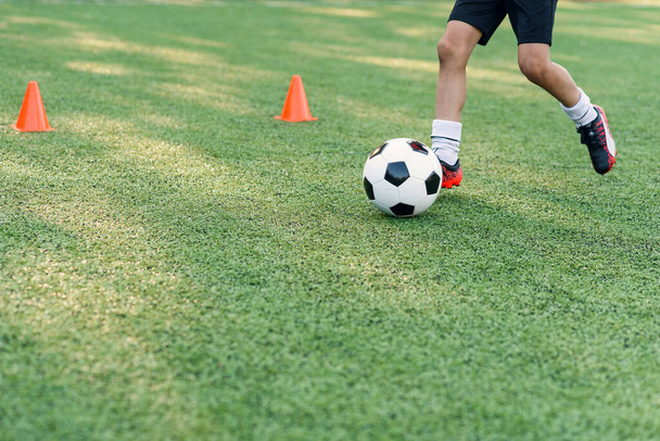 Soccer player kicking ball on field. Soccer players on training session. Close up footballer feet kicking ball on grass. - Foto, afbeelding