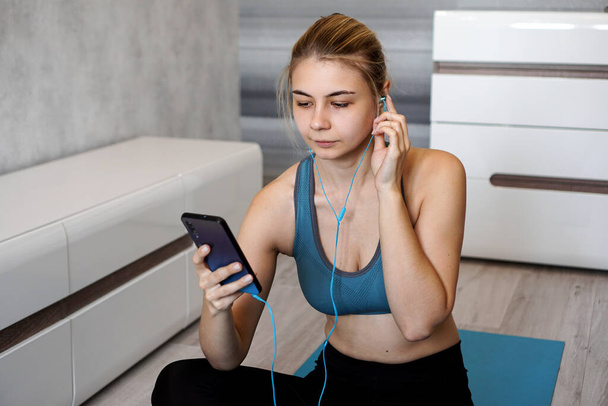 Sport woman with earphones enjoying the music playing while sitting on the floor - Photo, image