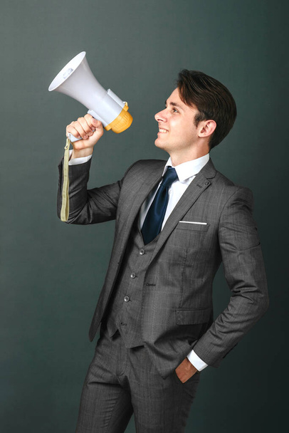 Business and finance concept. Portrait of a businessman who holds a megaphone in his hands. Light background - Foto, immagini