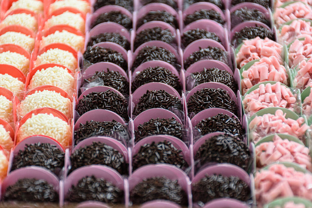 Traditional brigadiers (chocolate), alongside red fruit and white chocolate brigadiers. Organized in rows (side view). - Photo, Image