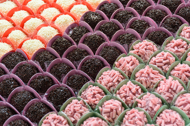 Traditional brigadiers (chocolate), alongside red fruit and white chocolate brigadiers. Organized in rows (top view). - Photo, Image