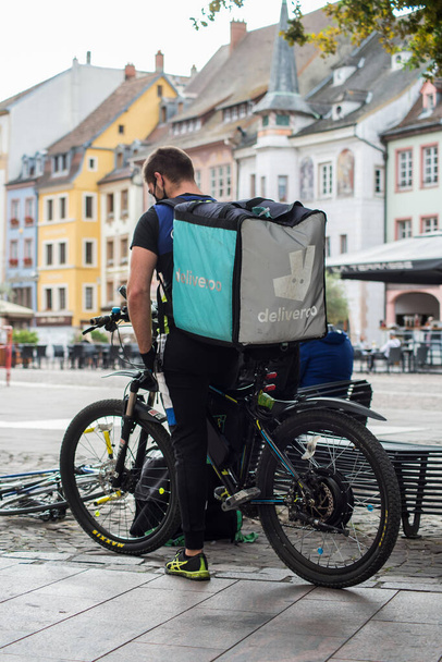 Mulhouse - France - 24 September 2020 - Delivery man standing with smartphone  in the street,  deliveroo is a british delivery company  in mountain bike  - 写真・画像